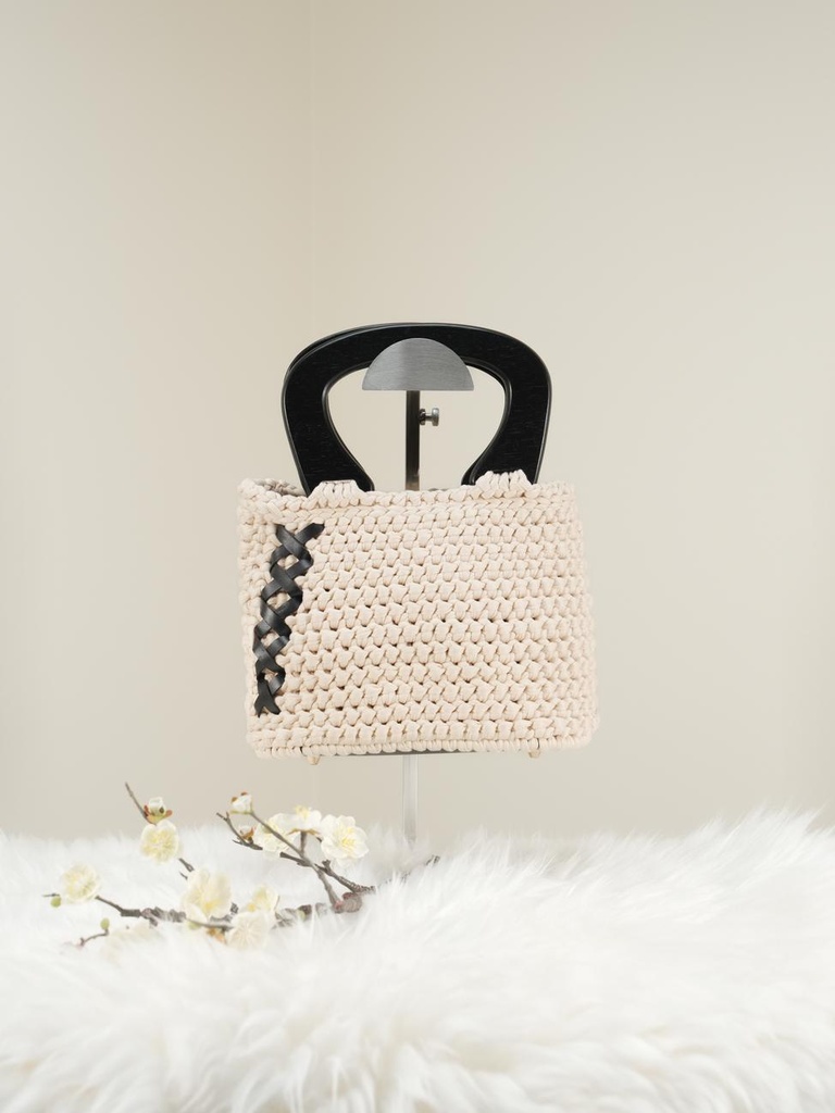 حقيبة بيضاء مائلة إلى الصفرة مع مقابض خشبية سوداء وجلد